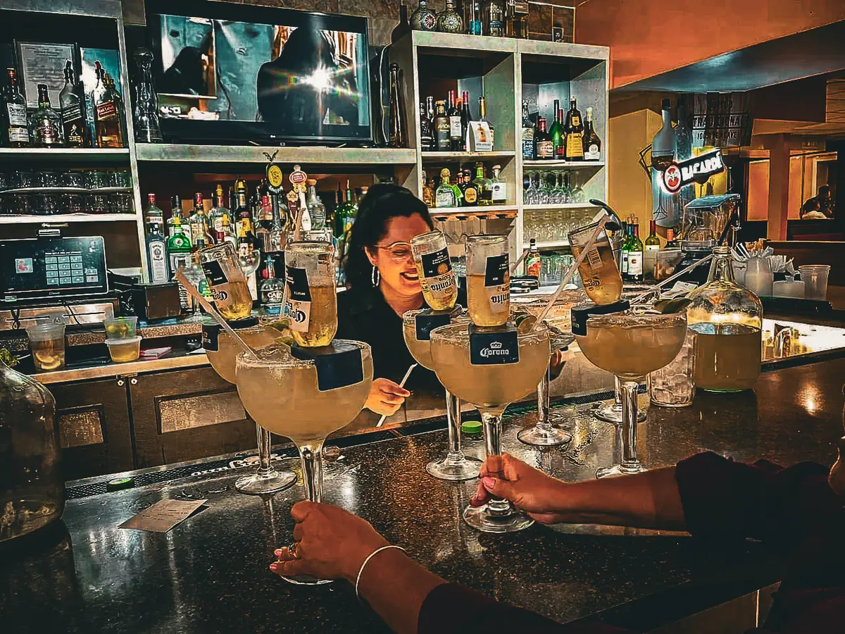 A bartender lining up jumbo margaritas on the bar