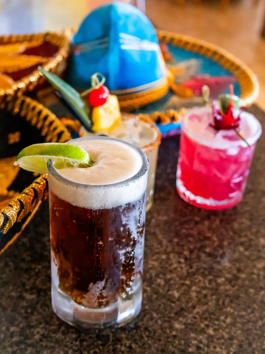 A beer and a hibiscus margarita in front of a sombrero